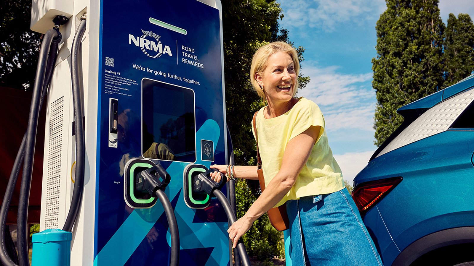 A white Tesla Model Y parked in a marked on-street electric vehicle charging bay on a Sydney suburban street.